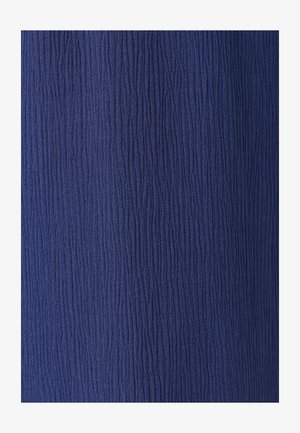 Dunkelblauer Stoff mit dichter, vertikaler, zerknitterter Textur, die ein wellenförmiges Oberflächenmuster erzeugt.