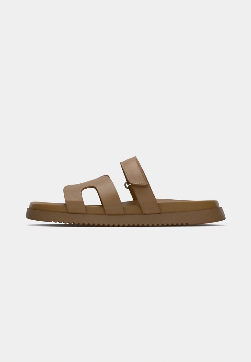 Braune Sandalen mit zwei breiten Riemen, einem Ausschnittdesign und einer strukturierten Sohle. Hergestellt aus glattem Material mit einer flachen, gepolsterten Fußbett.