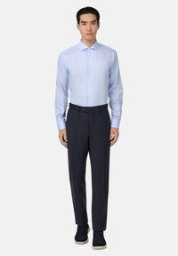 Lichtblauw gestreept overhemd met een spread collar en lange mouwen, gecombineerd met donkerblauwe op maat gemaakte broeken en donkere sneakers.