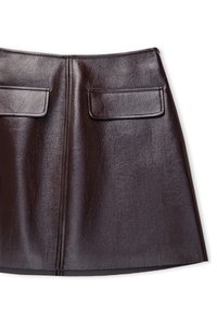 Mini-jupe trapèze en faux cuir marron foncé avec deux poches à rabat sur le devant et une couture verticale apparente au centre.