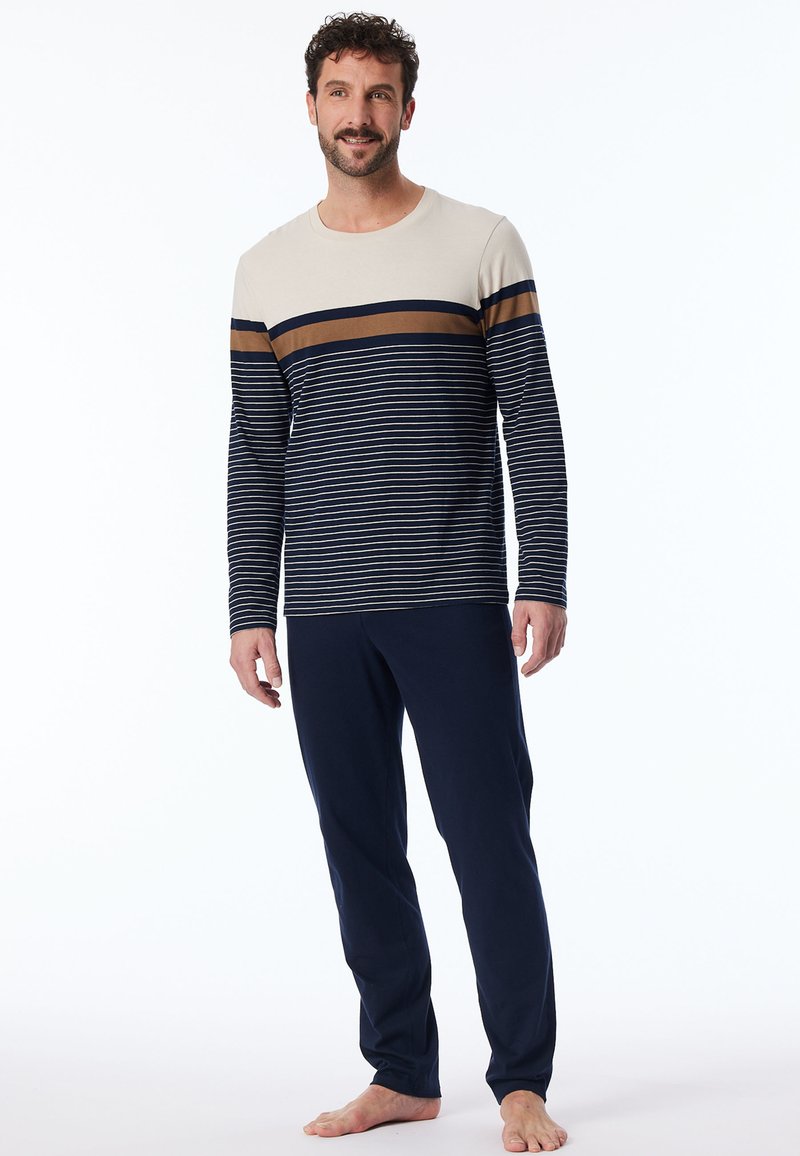 Marineblaues Pyjama-Set mit einem cremefarbenen und marineblauen gestreiften Langarmoberteil mit braunen Akzenten, kombiniert mit einfarbigen marineblauen Hosen. Aus weichem Baumwollstoff.