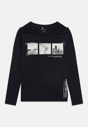 Sort langærmet hættetrøje med tre sort-hvide fotos og hvid tekst, inklusive "Urban Free Style" og skateboarding-tema sætninger.