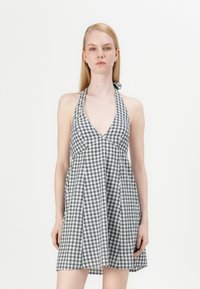 Rochie halter cu carouri alb-negru, cu guler în V adânc, fustă evazată și legături la gât. Material din bumbac, ușor și aerisit.