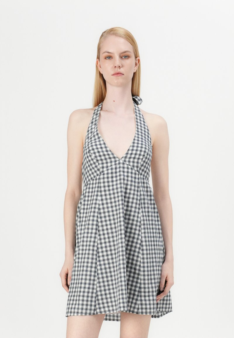 Rochie halter cu carouri alb-negru, cu guler în V adânc, fustă evazată și legături la gât. Material din bumbac, ușor și aerisit.