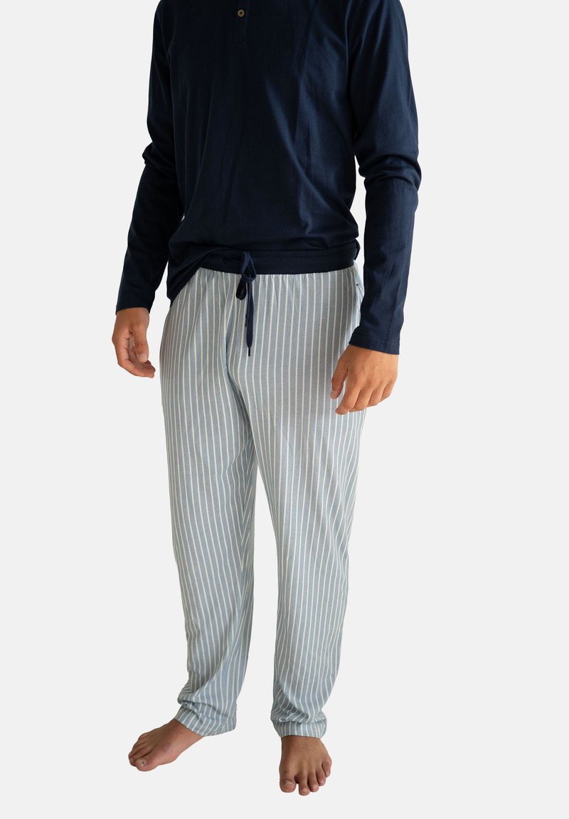 Granatowa koszula na guziki z długim rękawem w połączeniu z jasnoniebiesko-białymi pasiastymi spodniami do piżamy. Tkanina wydaje się miękka, z elastycznym pasem.