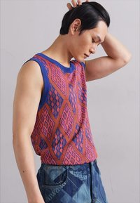 Top senza maniche in maglia con un motivo geometrico rosso e blu, dotato di scollo a coste e una vestibilità ampia. Abbinalo a jeans in denim.