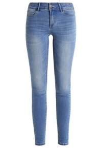 Kapeat siniset farkut, joissa on haalistunut pesu, viisi taskua ja napilla sekä vetoketjulla varustettu kiinnitys vyötäröllä.