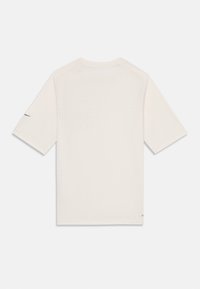 T-shirt à manches courtes, crème, avec un motif texturé, col rond et un petit logo noir sur la manche gauche.