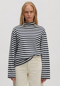 Gestreiftes Langarmoberteil mit hohem Ausschnitt in Marineblau und Weiß. Weicher Stoff, entspannter Schnitt und leicht übergroße Ärmel.