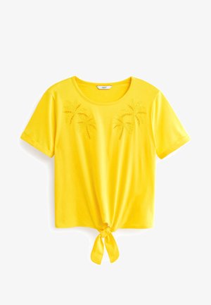 T-shirt jaune à manches courtes avec un col rond, brodé de palmiers sur le devant et un détail noué à l'ourlet.