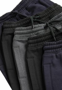 Vier Paar Jogginghosen in Dunkelblau, Schwarz, Dunkelgrau und Hellgrau. Jede Hose hat eine weiche Textur, einen elastischen Bund und Taschen.