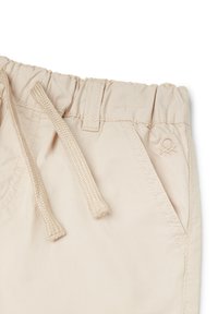 Pantaloni corti beige con vita elasticizzata, dotati di cordoncino e tasche frontali. Logo ricamato sottile sul lato. Tessuto liscio e leggero.