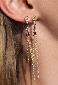 Boucles d'oreilles dorées avec des clous floraux, des accents bleus et roses, et des chaînes texturées en cascade en trois brins.