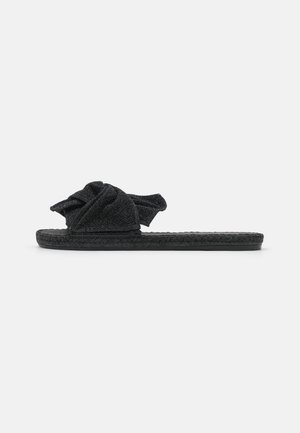 Sandale en tissu noir avec un design supérieur noué, surface texturée et semelle tissée avec un profil plat.