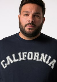 Námorní modré bavlněné tričko s nápisem "CALIFORNIA" v tučných bílých písmenech přes hruď, kulatým výstřihem a krátkými rukávy.