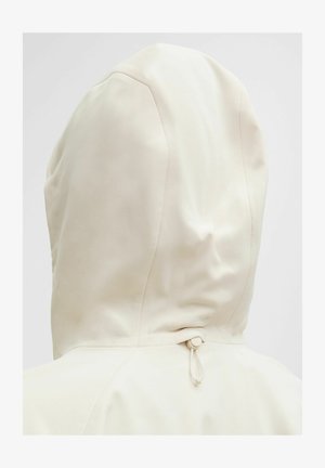 Světle krémová mikina s kapucí, hladkého povrchu a s nastavitelným stahovacím šňůrkou na zádech, která zdůrazňuje minimalistický design.