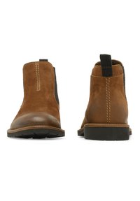 Bottines Chelsea en daim marron avec des panneaux latéraux élastiques, des détails de couture contrastés et des semelles en caoutchouc. Bout arrondi et languette à l'arrière.