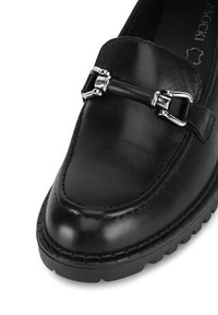 Czarne skórzane mokasyny z zaokrąglonym noskiem, z metalowym akcentem w kolorze srebrnym oraz przeszyciami na podeszwie, które dodają tekstury.