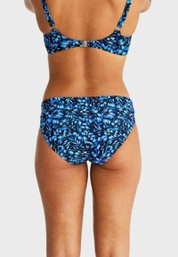 Blå blommönstrad bikini med justerbara axelremmar och spänne. Har tropisk motiv i varierande nyanser av blått på mjuk tyg.