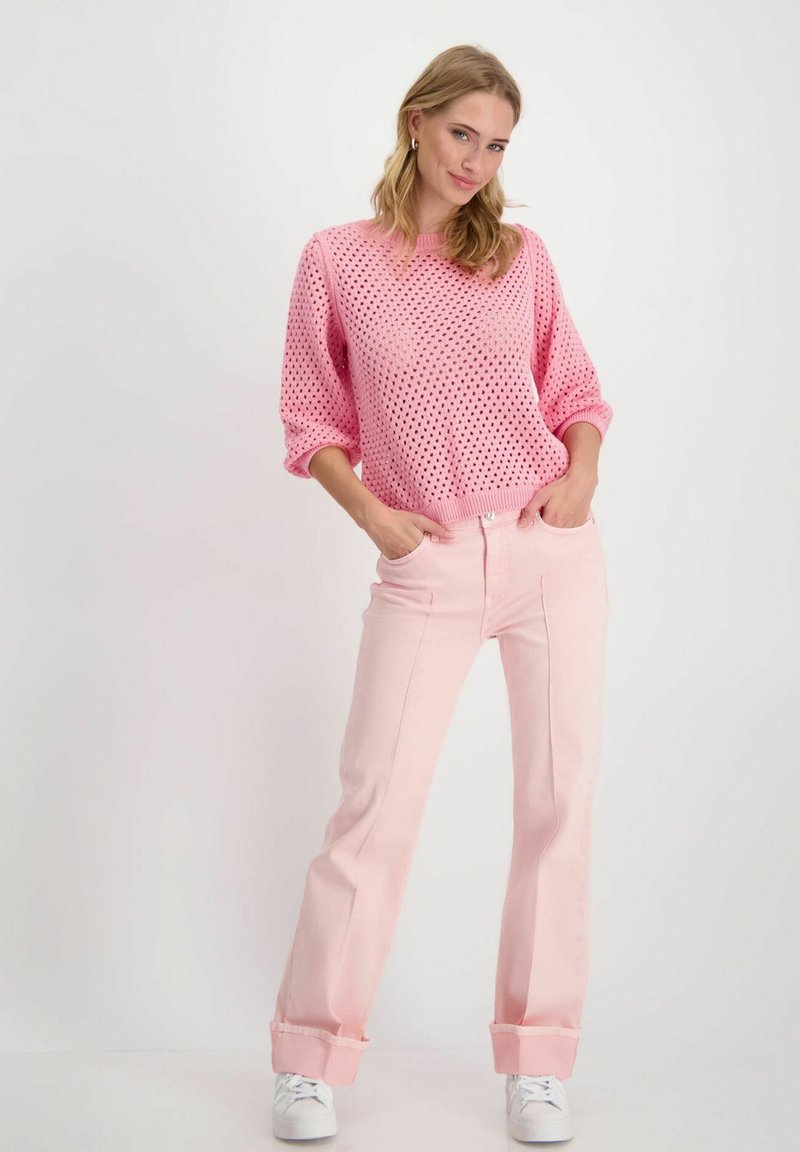 Pull en tricot rose à coupe ample et motif en diamant, assorti à un pantalon rose droit à ourlet au bas et des baskets blanches.