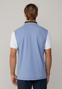 Blaues Polohemd mit kurzen Ärmeln, navyfarbener Kragen und weißen Ärmeln. Glatte Textur, Rückansicht zeigt ein sauberes Design mit sichtbaren Nähten.