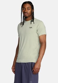T-shirt atletico verde chiaro a maniche corte realizzato in tessuto traspirante. Presenta un logo discreto sul petto e lati testurizzati.