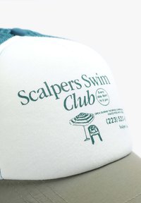 Caciulă de baseball albă cu spate din plasă teal, având textul "Scalpers Swim Club", o grafică cu un umbrar și un scaun, și o vizieră bej.