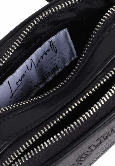 Pochette en cuir noir avec fermeture éclair en métal argenté et une étiquette intérieure portant les inscriptions « Love Yourself » et « ZADIG & VOLTAIRE ».