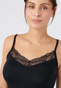Black camisole featuring a lace trim neckline in a scalloped pattern, thin straps, and a soft, smooth fabric.