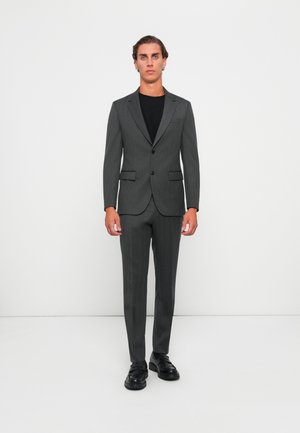 Gray tailored suit with a slim fit, single-breasted jacket, notch lapels, matching pants, and black shoes. Smooth fabric with subtle texture.