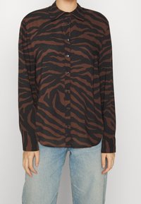 Brown and black striped long-sleeve shirt with a button-up front and pointed collar, made of lightweight fabric. Features a relaxed fit.