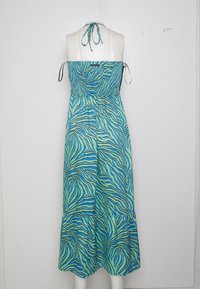 Robe maxi sans bretelles en imprimé zèbre bleu et vert, avec un corsage smocké et une jupe évasée à ourlet froncé. Bretelles noires à nouer aux épaules.