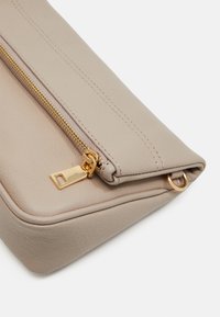 Clutch in pelle beige con superficie texturizzata, zip dorata e dettagli accentuati. Presenta una forma rettangolare e cuciture visibili.