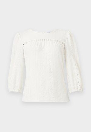 Valkoinen pitkähihainen pusero, jossa rei'itetty kuvio, kuminauhakärjet, kerrostettu olkasauma ja pyöreä pääntie.