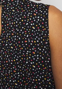 Tessuto nero con un motivo a pois multicolori, che presenta punti gialli, rossi, blu, rosa e bianchi. Texture liscia, design senza maniche.
