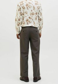 Košile s květinovým vzorem v bílé, béžové a hnědé barvě, kombinovaná s tmavě šedými kalhotami. Kalhoty mají dvě zadní kapsy a rovný střih.