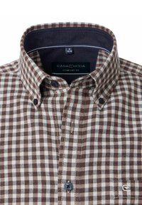 Hemd mit knöpfbarem Kragen in einem braun-weißen Karomuster. Hat einen klassischen Kragen, zwei Knöpfe am Hals und ein Komfortschnitt-Etikett.