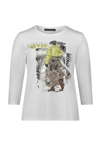 Weißes Langarmshirt mit einem grafischen Druck eines Figures in einer grünen Steppjacke und einem gemusterten Rock mit dem Text "NEVER."