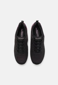 Zapatillas Skechers negras con un upper de punto texturizado, que presentan acentos coloridos, cordones elásticos y una plantilla acolchada de "Memory Foam".