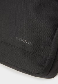Černá látková taška s texturovaným povrchem a jemně embosovaným logem "BJORN BORG" na jedné straně. Kompaktní design a minimální kovové doplňky.