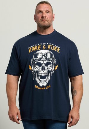 Homme portant un t-shirt bleu marine avec un grand crâne portant des lunettes et le texte "Fire & Fuel Motorcycle Club" sur le devant.