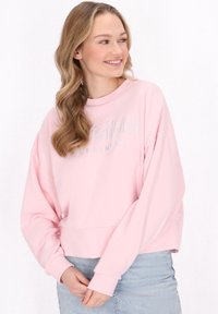 Felpa rosa chiaro con collo rotondo e design a spalla scesa, caratterizzata da testo testurizzato "visible" e "happiness" in un blu chiaro a contrasto.