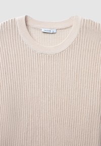 Maglione a maglia leggero beige con una texture a coste e un colletto rotondo. Presenta un'etichetta che indica la taglia L. Il tessuto sembra morbido e traspirante.
