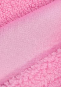 Różowy materiał z teksturowanym włosiem z jednej strony i gładkim materiałem przypominającym bawełnę z drugiej, prezentujący różne odcienie różu.