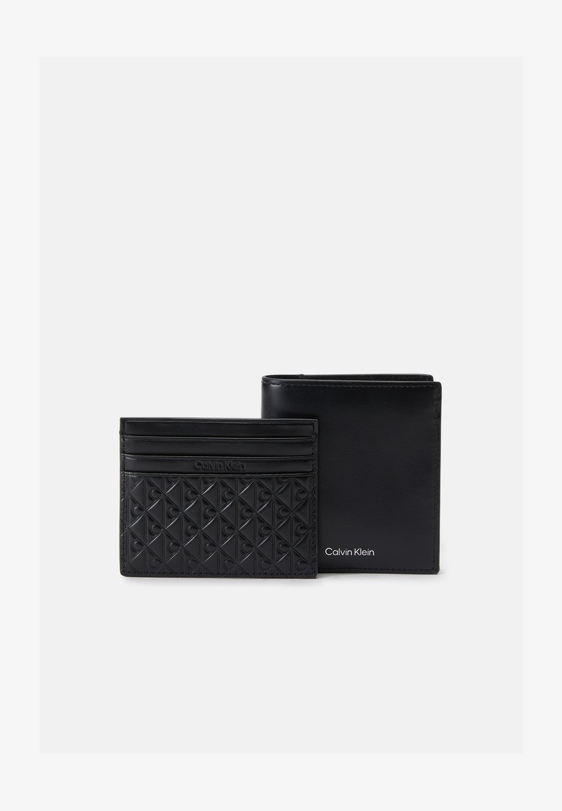 Conjunto de cartera y tarjetero de piel negra. Patrón texturizado en el tarjetero; acabado suave en la cartera. Ambos presentan el logo grabado de Calvin Klein.