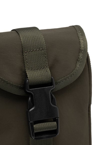 Rabats de sac à dos kaki avec boucle en plastique noire, en tissu durable et avec des bords cousus. Sangle texturée visible sur le dessus.