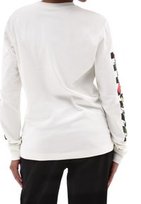 Wit longsleeve t-shirt van katoen, met een bloemenpatroon op de zwarte accenten van de mouwen en een ronde halsline.