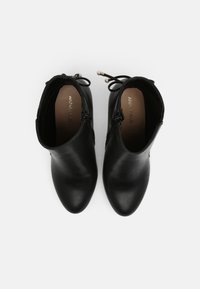 Stivaletti neri alla caviglia in pelle liscia con punta appuntita e cerniera laterale. Presentano un lacci decorativo con accentuazione di perle sul retro.