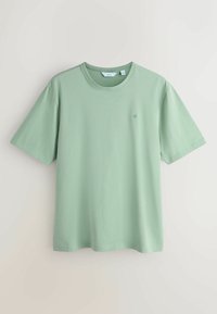 T-shirt vert clair en coton à manches courtes, col rond, avec un petit logo de couronne brodé sur la poitrine gauche, présenté à plat sur un fond blanc.