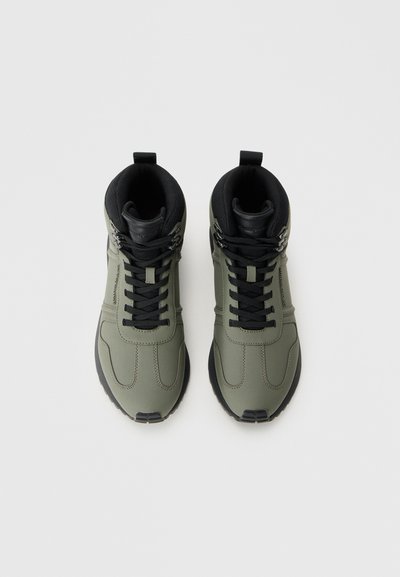 Green high-top sneakers with smooth synthetic upper, black accents, flat laces, and padded collar for comfort. Rubber sole with texture details.